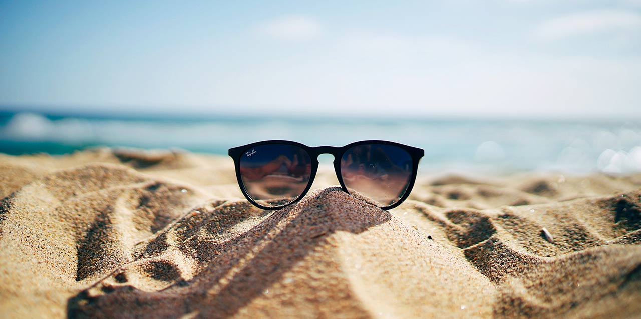 óculos em montinho de areia na praia